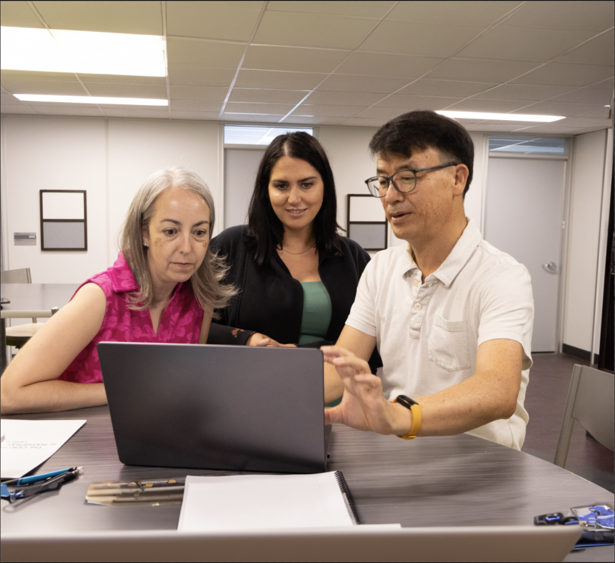 Adults looking into a laptop and discussing something