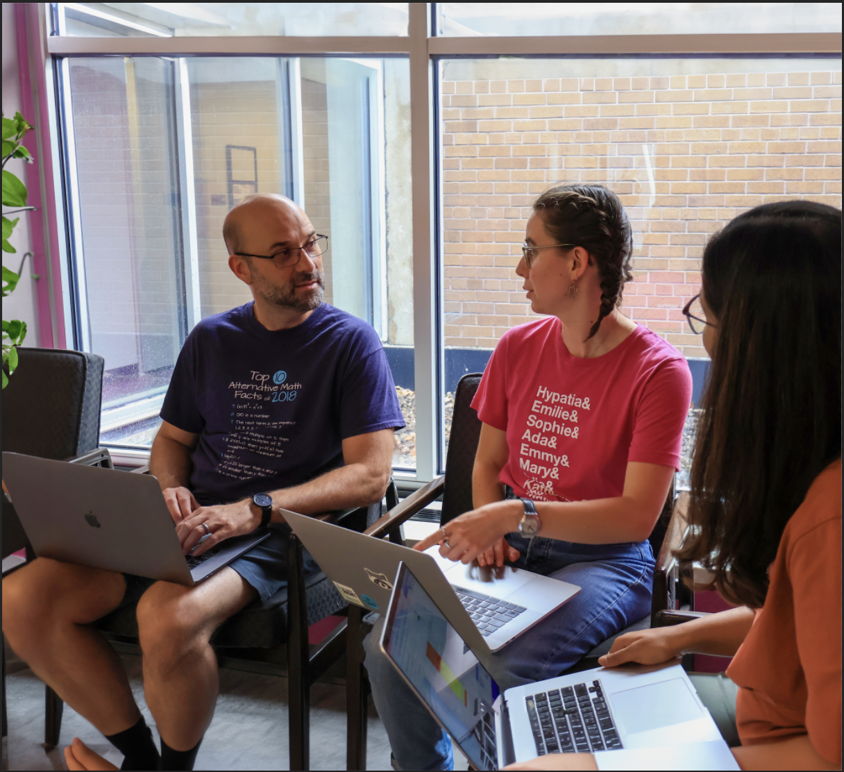 Two adults talking to each other with laptops open 