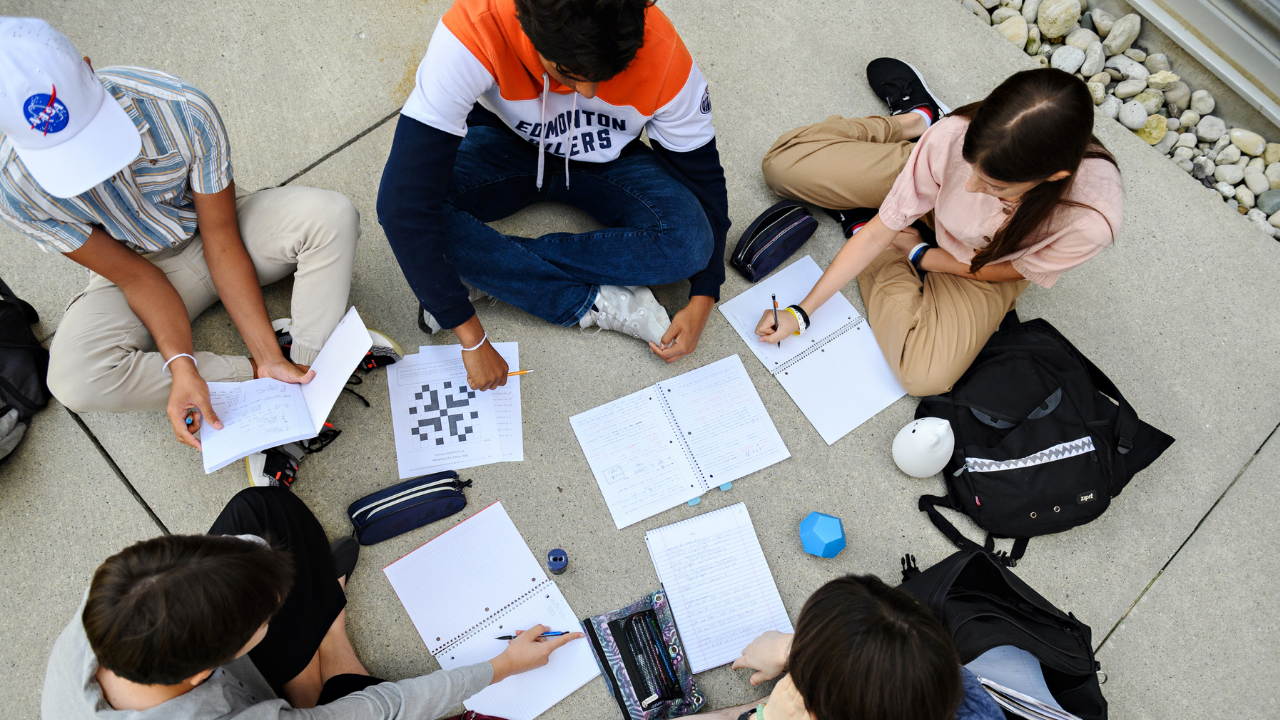 Group of students collaborating on math and computing problem solving outdoors