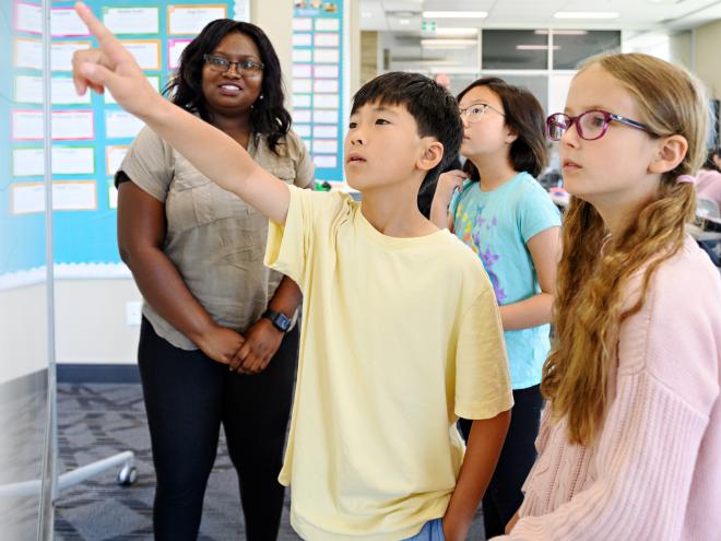 Students problem solving on a white board with an educator