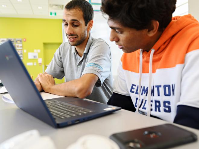 Educator helping student understand a computer science program on the laptop